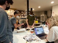a group of people standing around a table with a laptop